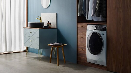 En Electrolux vaske og tørremaskine placeret i et klædeskab under en bøjlestang.