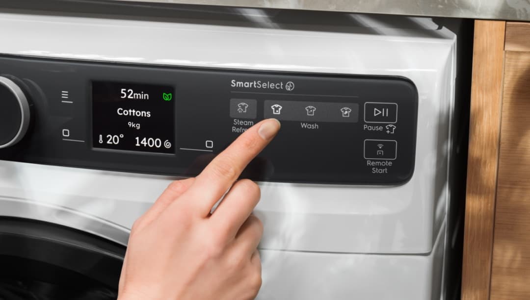 Hånd der justerer indstillingerne på en Electrolux vaskemaskine.