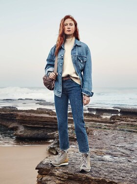 Kvinde står på sten i jeans
