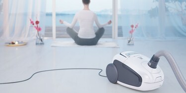 En kvinde laver yoga med sin Electrolux Ultra Silencer-støvsuger i forgrunden