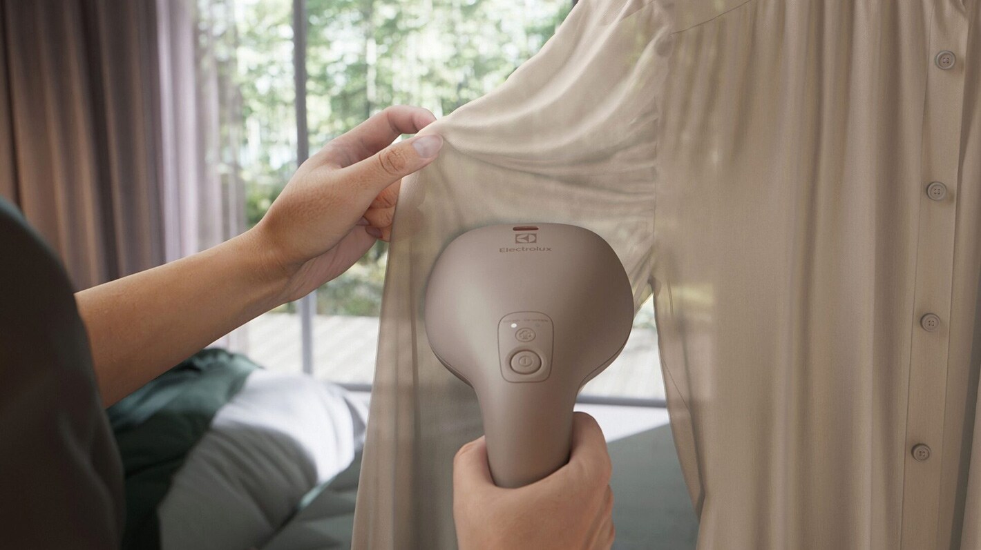 Lys skjortebluse bliver steamet mens den hænger på en bøjle.