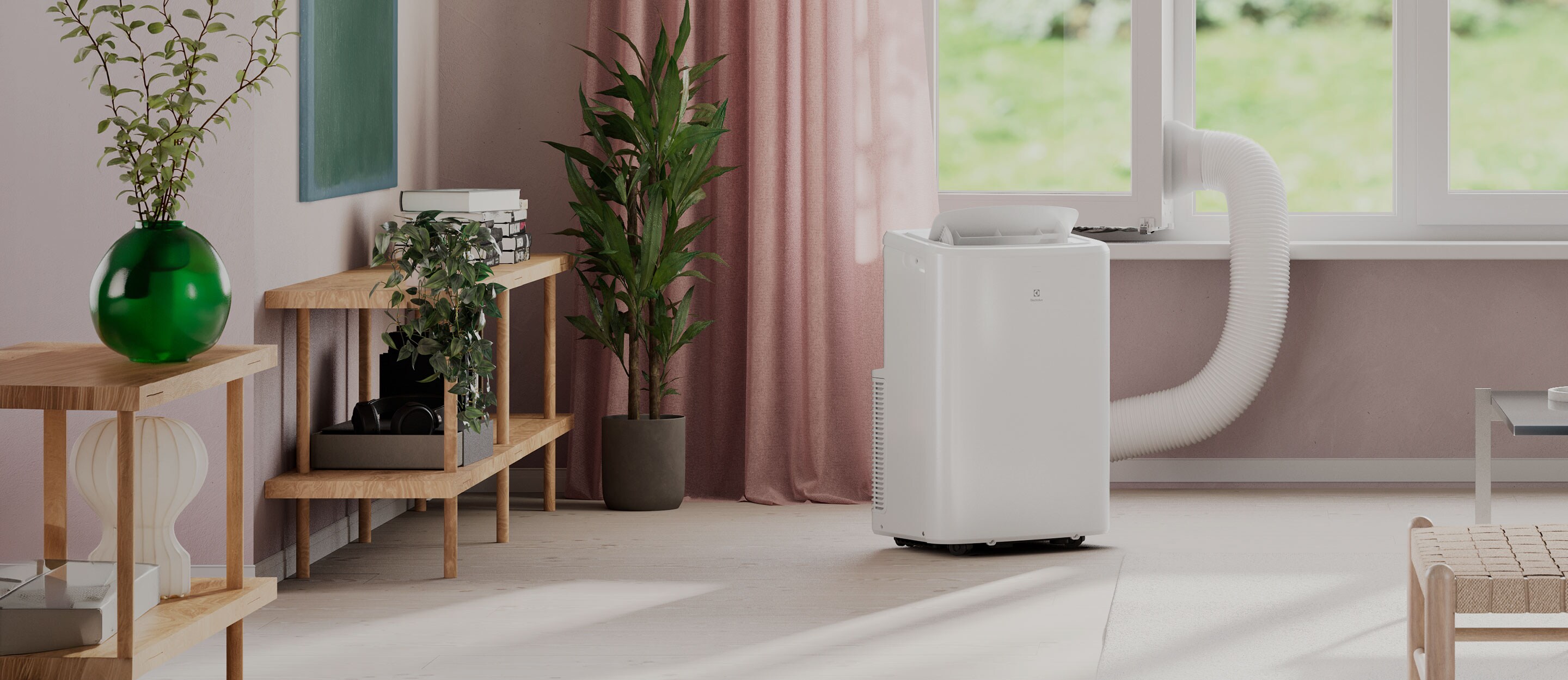 Kompakt, mobil Electrolux aircondition ved et vindue. Den køler rummet effektivt og leder varm luft væk via en slange.