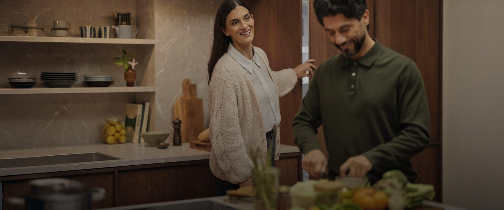 Et par der laver mad i et moderne køkken med integrerede hvidevarer fra Electrolux.