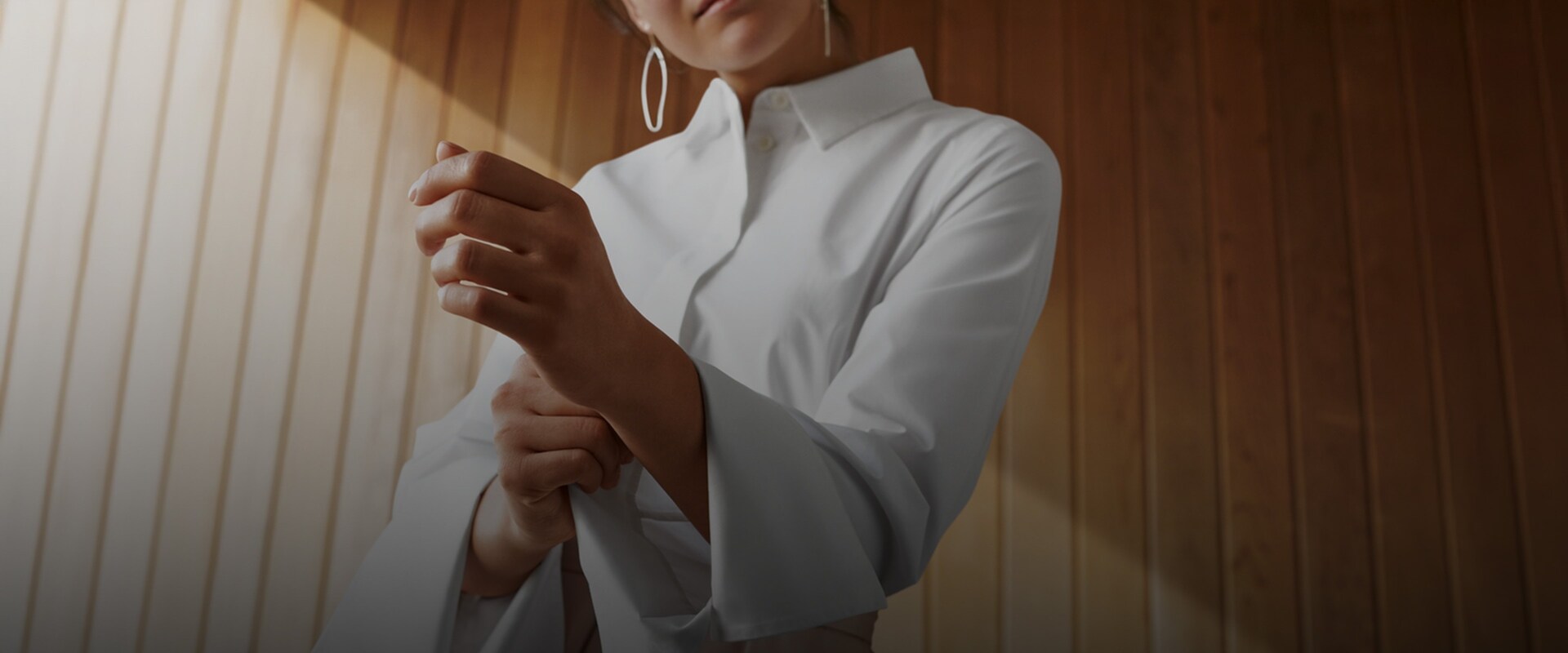 En kvinde der folder ærmet op på en hvid skjorte.