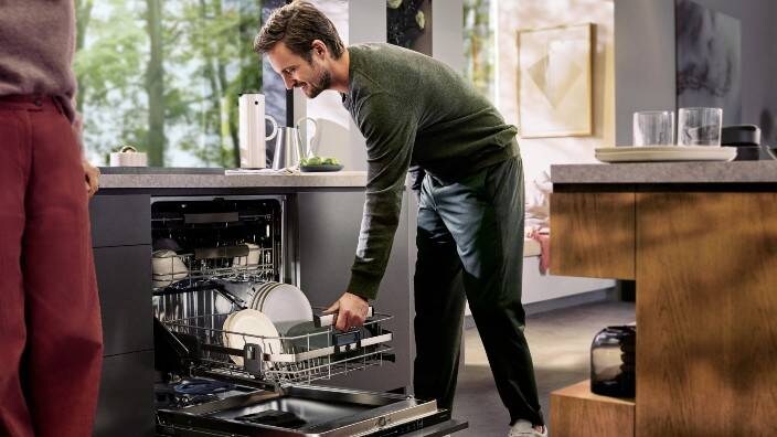 En mand tømmer opvaskemaskinen