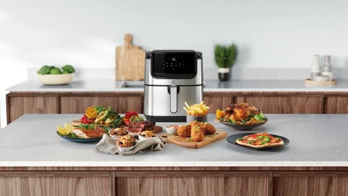 Olika maträtter står uppdukade framför en Airfryer från Electrolux.