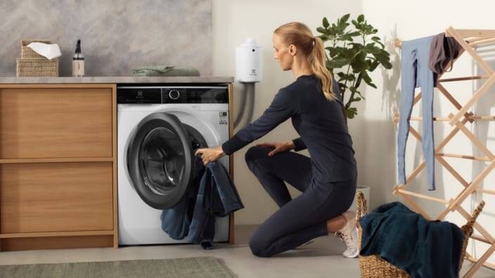 kvinde lægger vasketøj ind i en vaskemaskine